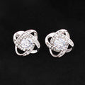 Pair of 14k white gold plated Love Knot stud earrings featuring sparkling cubic zirconia center stones on a dark background