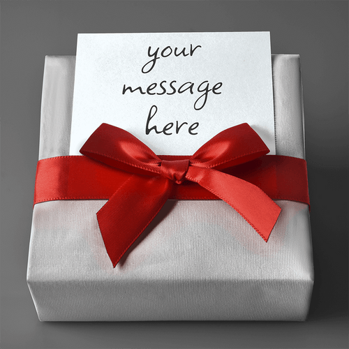 Close-up of hand-wrapped gift box with red ribbon and custom personalized message card